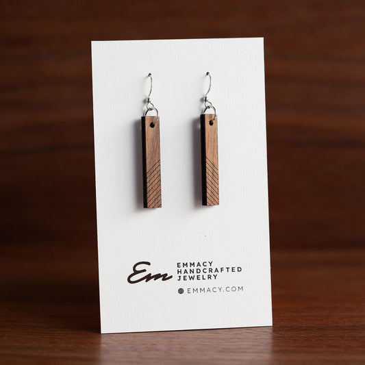 Laser cut wooden dangle earrings in the shape of a narrow rectangle with angled score lines along the bottom half.